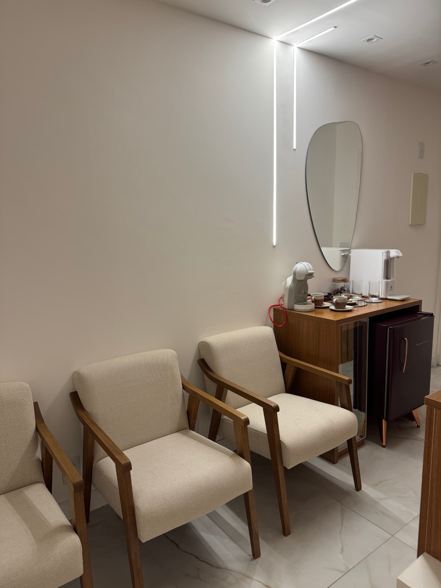Sala de espera do consultório com poltronas claras e estação de café